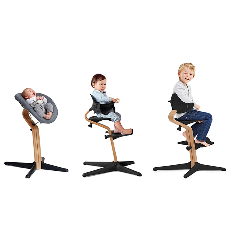 Nomi Hochstühle mit Babyaufsatz, Kleinkindersitz und Kindersitz von Stokke mit schwarzem Sitz und Mittelbalken aus Holz. 
