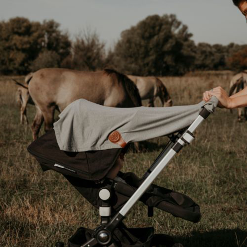 Sonnenschutz-Tuch befestigt an schwarzem Kinderwagen mit braunem Magnetclip von Cloby. 