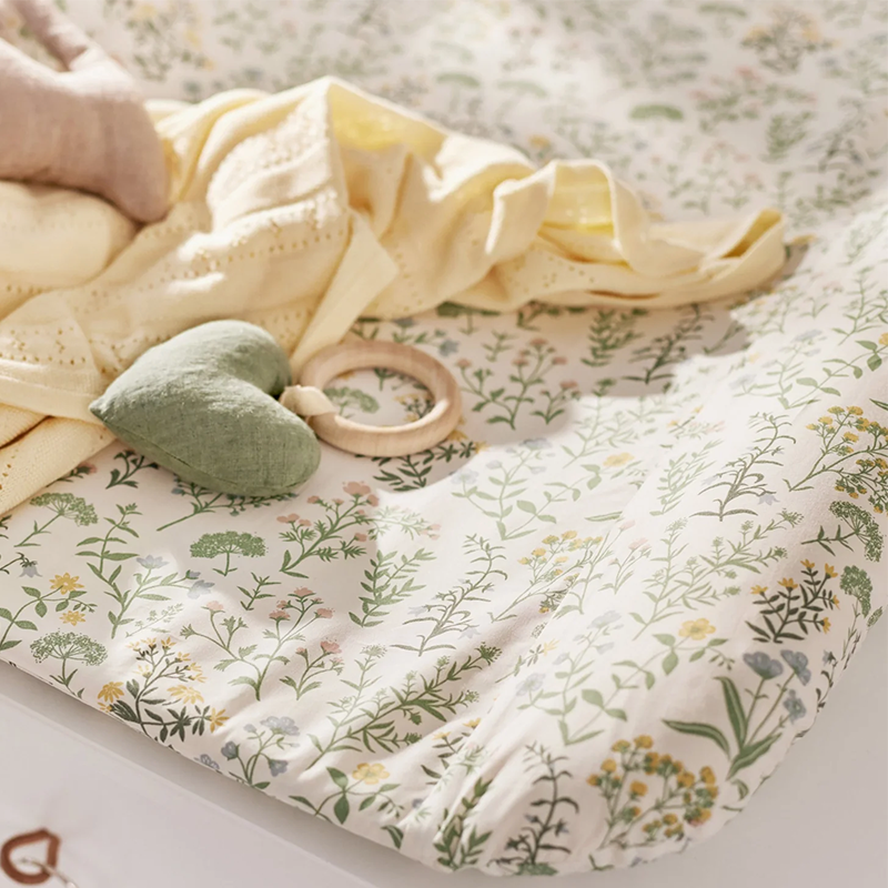 Wickelkissen von Dear April mit Blumenmuster auf einem Wickeltisch. 