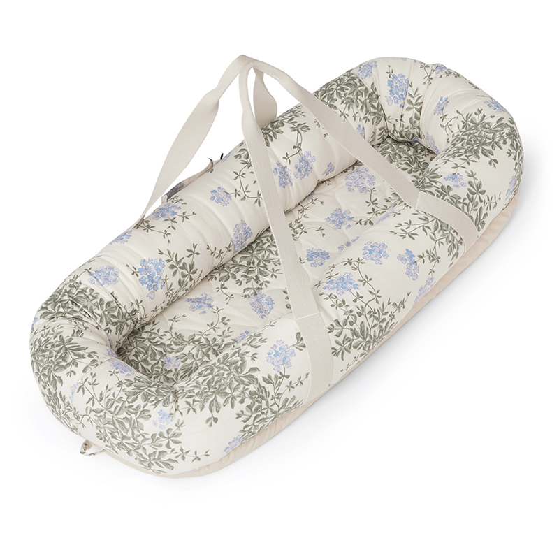 Babynest in Beige mit Tragegriffen und blau-grünem Blumenmuster von Garbo&Friends.