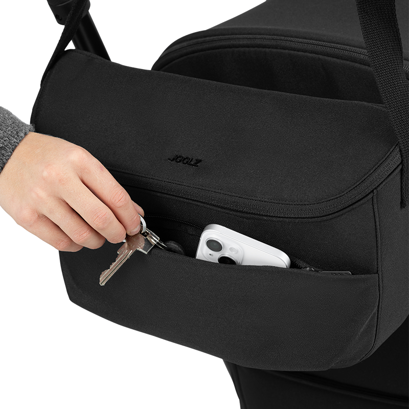 Joolz Kinderwagen Organiser in Schwarz hängt an Kinderwagen im Aussenfach ist Schlüssel und Handy platziert. 