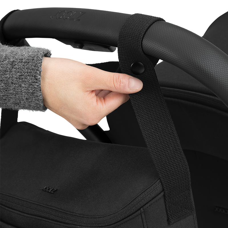 Joolz Kinderwagen Organiser in Schwarz wird gerade an Griff von Kinderwagen gehängt. 
