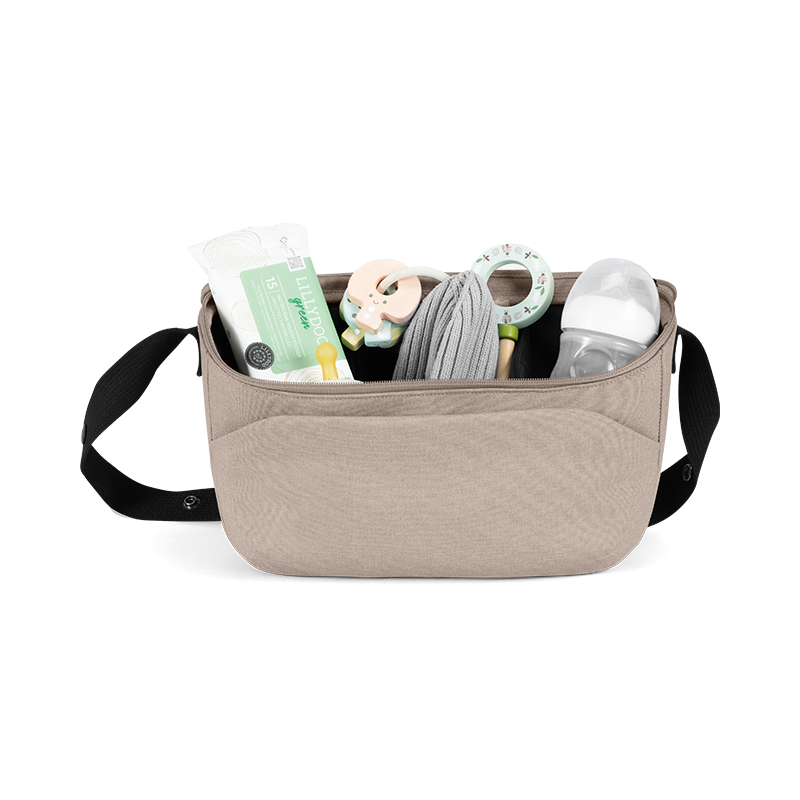 Offener Kinderwagen Organizer in Beige mit schwarzem Henkel von Joolz gefüllt mit Feuchttücher, Spielsachen und Flasche. 