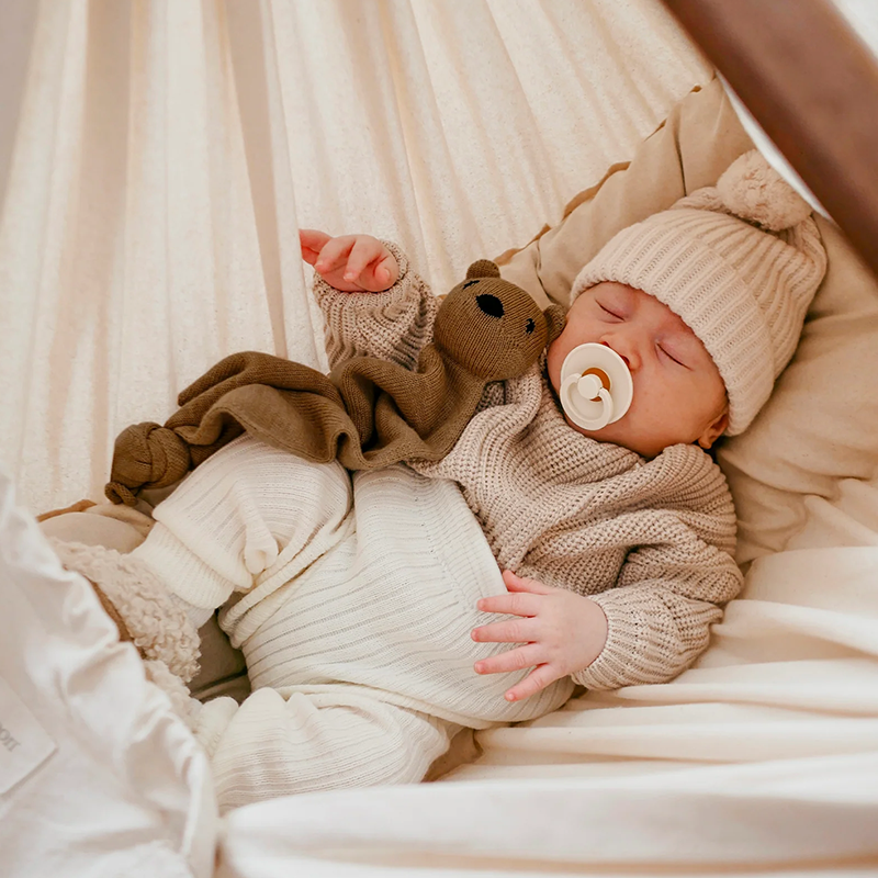 Baby liegt mit braunem Teddy in der Federwiege für Babys mit Gestell und Federwiegen-Motor von Moonboon.