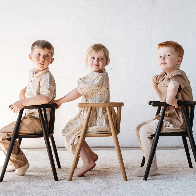 3 Kinder sitzen auf Oaklings 'STORM' Kinderstühlen in Oak und Smoked Oak. 