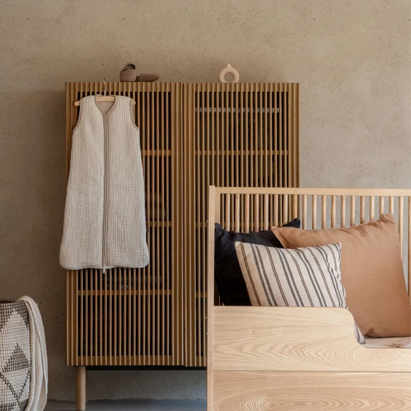 Kinderschlafsack in Beige von Quax hängt im Kinderzimmer am Kleiderschrank.
