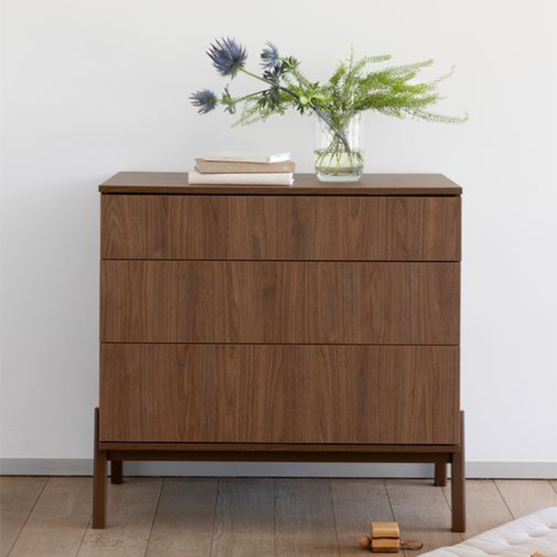Kommode mit 3 Schubladen in Kastanienbraun mit Füsse aus massiver Eiche von Quax, dekoriert mit einem kleinen Blumenstrauss und Büchern.
