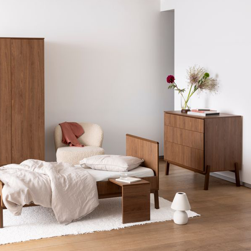 Kommode mit 3 Schubladen in Kastanienbraun mit Füsse aus massiver Eiche von Quax, steht in einem Kinderzimmer mit Schrank und Bett im gleichen Stil. Auf der Kommode steht eine Vase mit Blumen und Bücher.