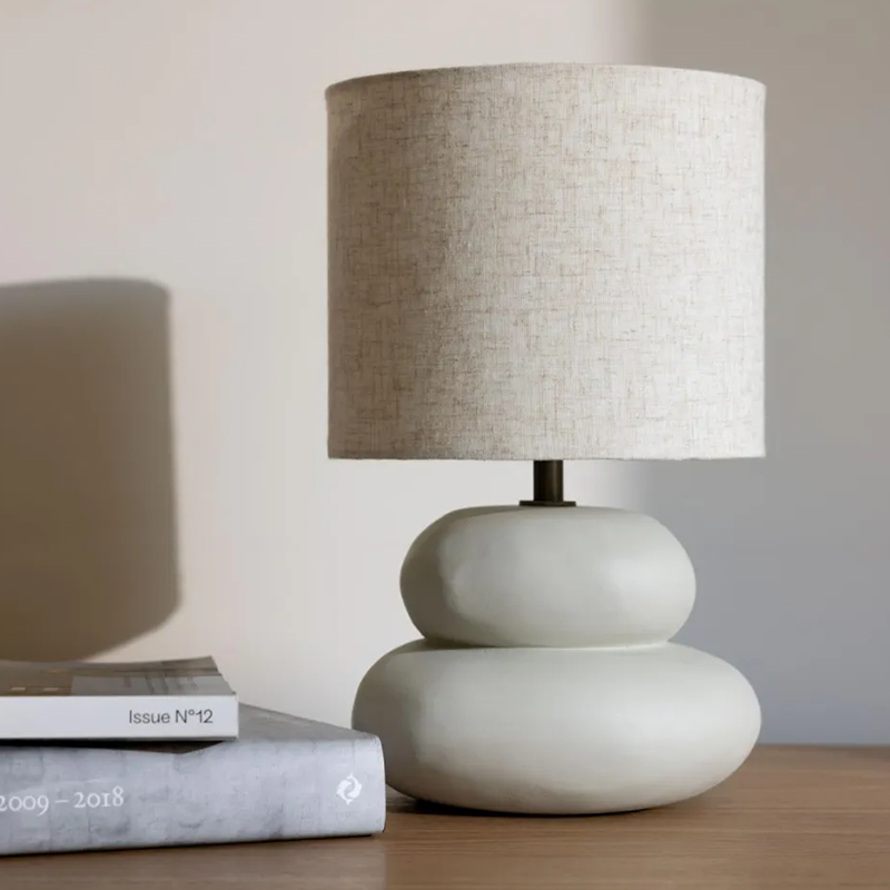 Tischlampe mit Lampenschirm in Beige von Quax. Die Lampe steht neben zwei Büchern.