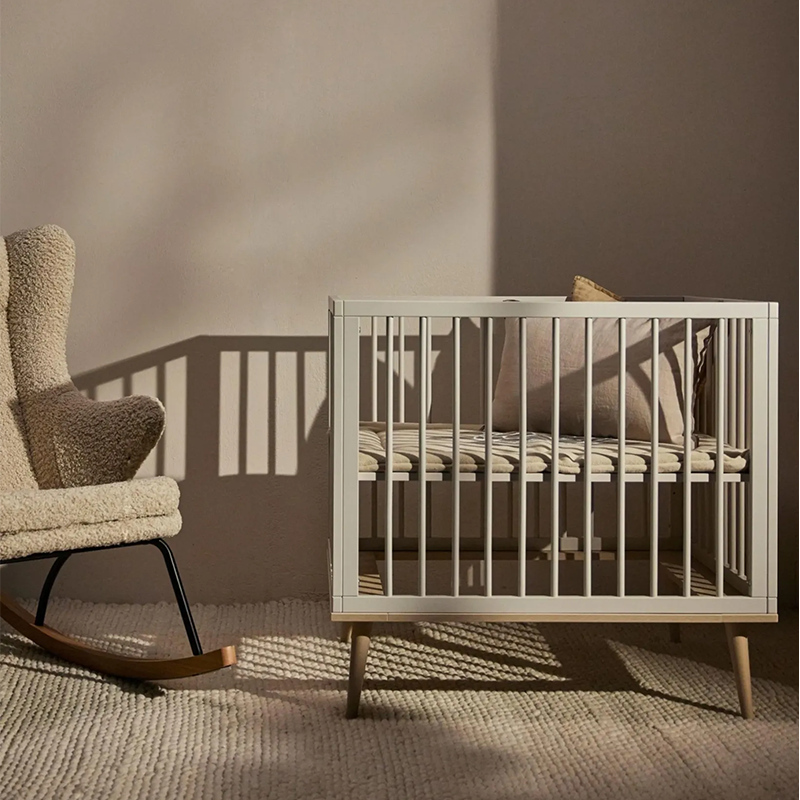Laufgitter in Beige mit Beinen aus Buchenholz  von Quax mit einem Kissen drin.