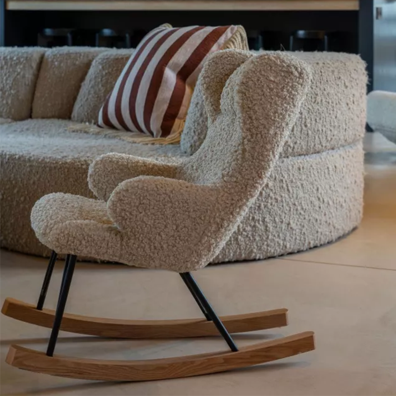 Schaukelsessel für Kinder mit Teddy-Stoff Bezug und Holzkufen von Quax neben einem Sofa mit gleichem Teddy-Bezug.