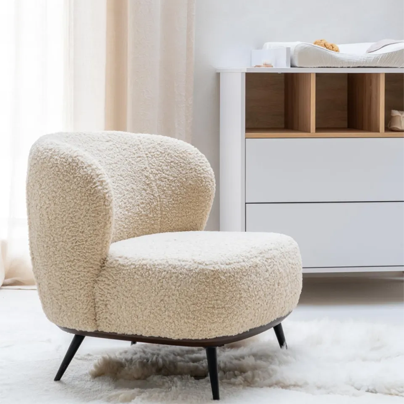 Loungesessel in Beige mit weichem Teddy-Bezug von Quax steht vor einem Wickeltisch.