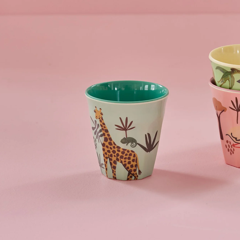 Melamin Becher für Kinder in Grün mit Giraffenprint von Rice steht neben 2 anderen Bechern auf einem pinken Untergrund. 