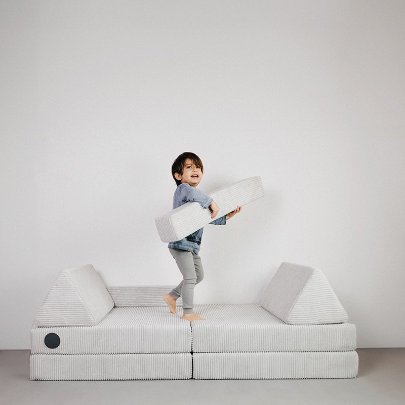 Kind spielt auf dem Spielsofa für Kinder in Grau aus Cordstoff von Wonderwuzz.