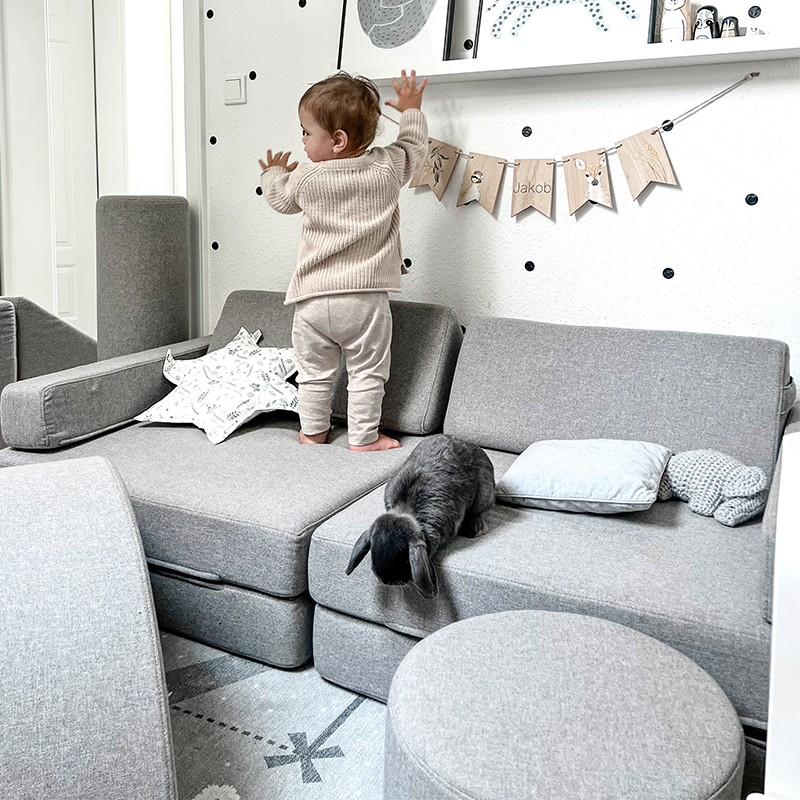 Wonderwuzz modulares Spielsofa 'OH SO SOFY' in der Farbe Grauffelo in einem Kinderzimmer mit Baby das darauf spielt. 