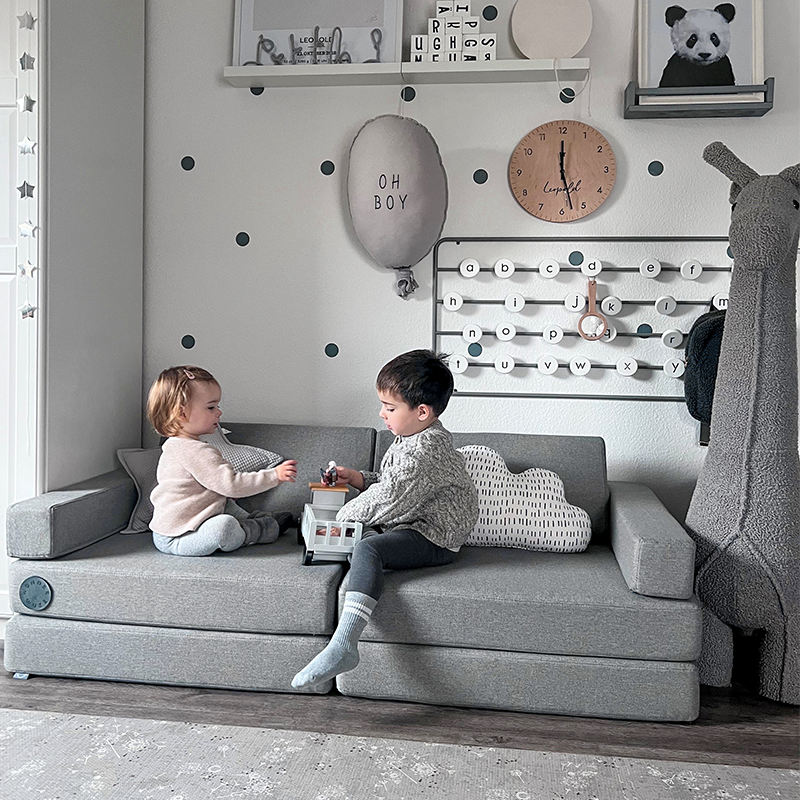 Wonderwuzz modulares Spielsofa 'OH SO SOFY' in der Farbe Grauffelo mit 2 Kinder, die darauf spielen. 