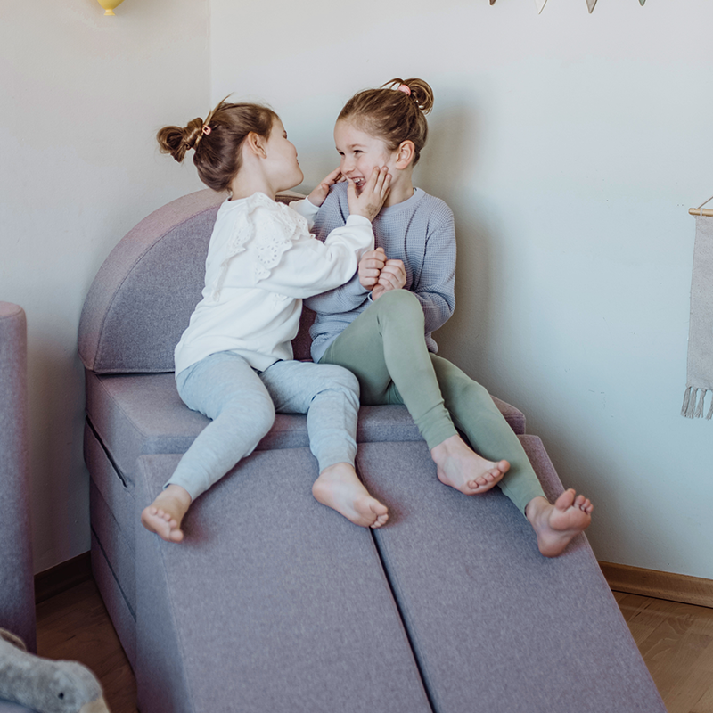 2 Mädchen spielen auf dem Wonderwuzz Spielsofa 'Oh so sofy' in der Farbe lilfafee